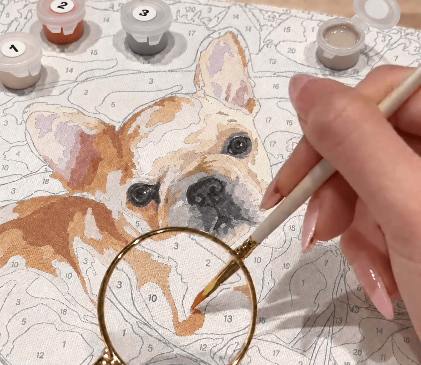 番号付きの絵の具とルーペを使い、下絵に色を塗る手元