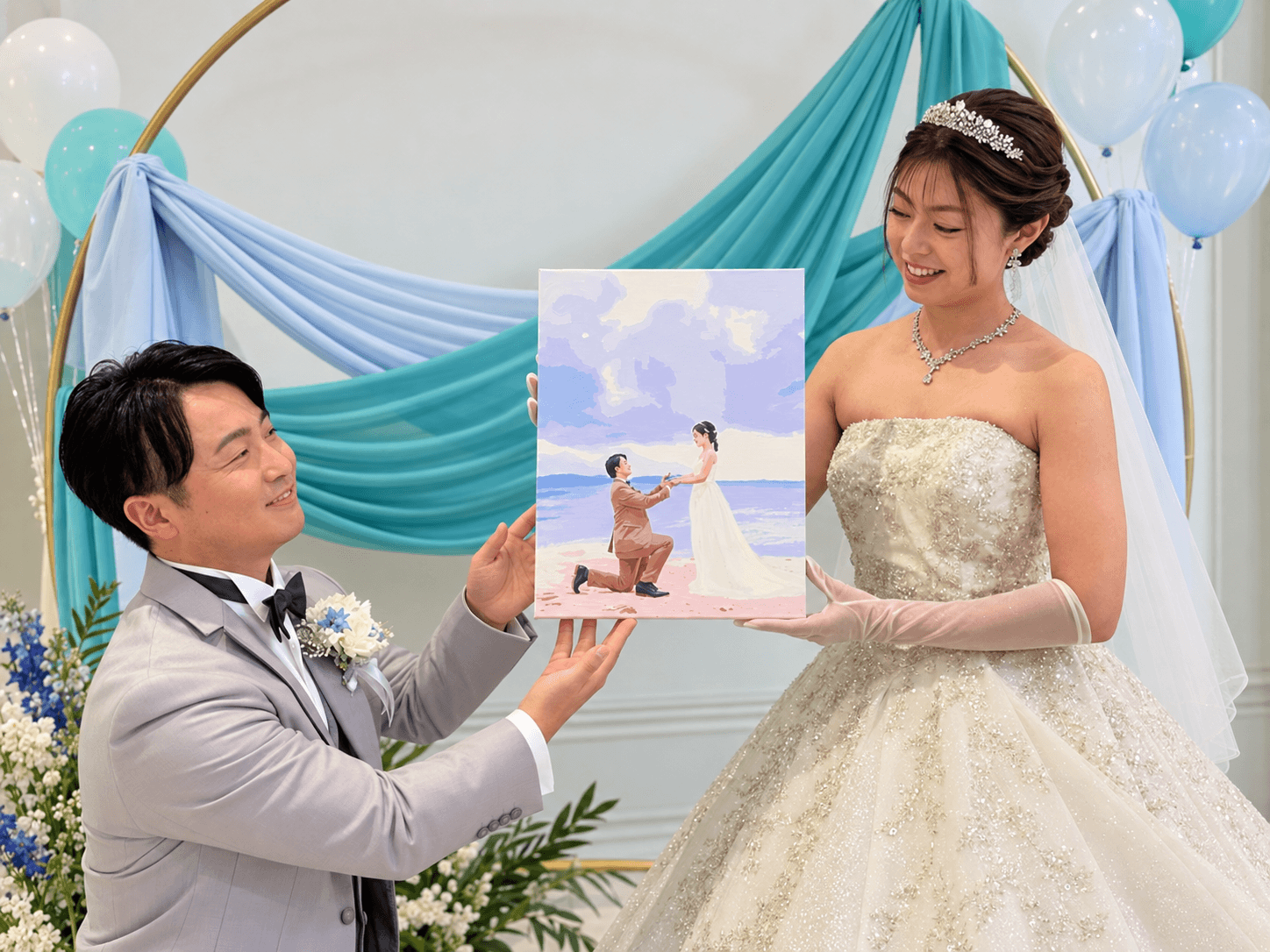 プロポーズシーンを描いた作品を手にするご夫妻
